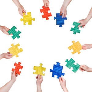 painted puzzle pieces in people hands in circle